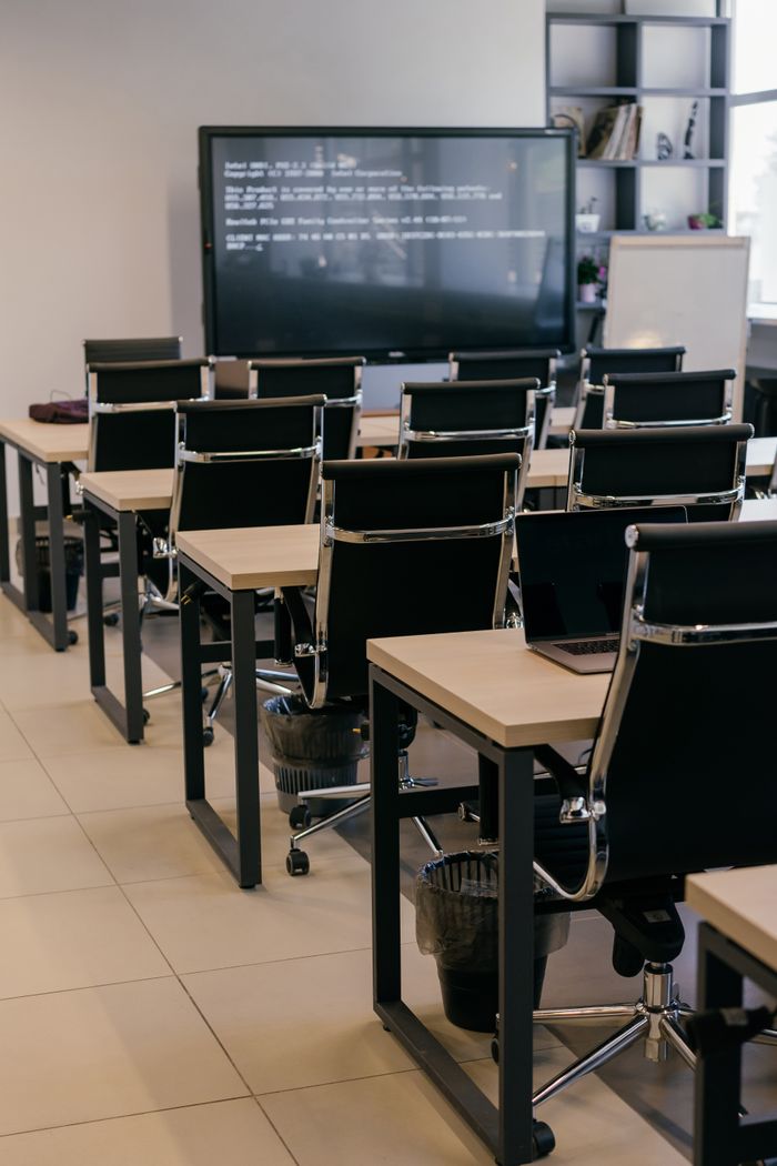 Contemporary office space with sleek black leather chairs and a large screen for presentations.